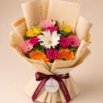 Colourful gerbera and pink rose bouquet in printed wrapping